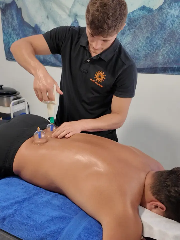Lloyd applying myofascial cupping cups to a client’s back at Reset Massage